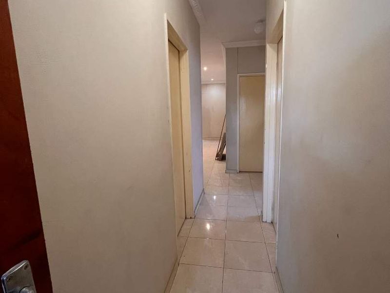 A functional hallway featuring tiled flooring, ceiling cornicing, and multiple internal doors leading to other rooms within the property.