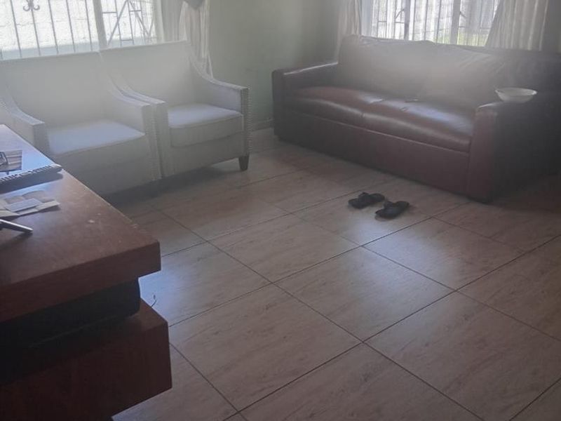 A living room featuring tiled flooring and windows fitted with security bars, offering a functional space with natural light.