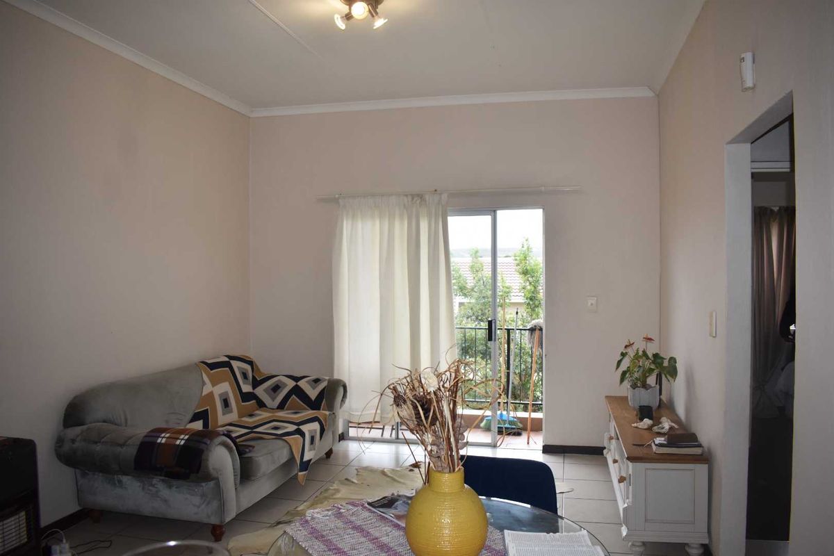 A living room featuring tiled flooring and a sliding glass door that provides access to an outdoor balcony area.