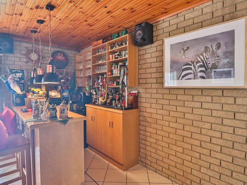 A dedicated bar area featuring exposed brick walls, timber ceiling, and built-in cabinetry with integrated shelving.