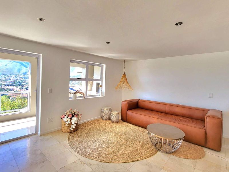 Bright and airy living room featuring tiled flooring, recessed downlights, and a sliding glass door leading to a balcony with scenic views.