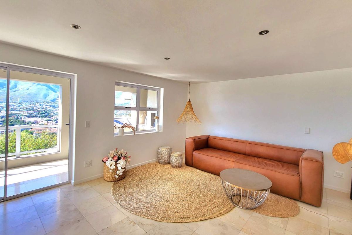 Bright and airy living room featuring tiled flooring, recessed downlights, and a sliding glass door leading to a balcony with scenic views.