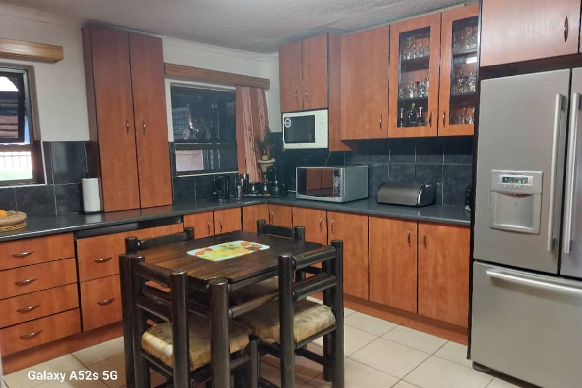A functional kitchen featuring wood-finish cabinetry, dark countertops, tiled backsplash, and integrated storage space, providing a practical layout for daily meal preparation.