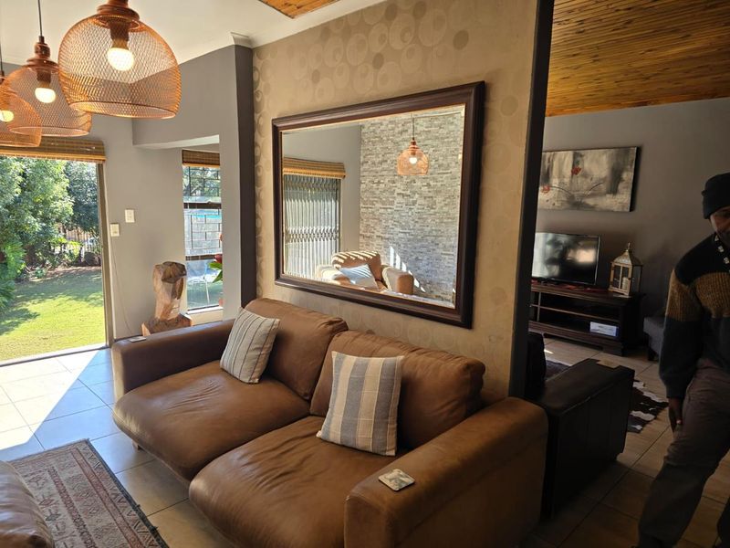 A comfortable living area featuring tiled floors, a timber ceiling, and a stone feature wall, with direct access to the garden through a sliding door.