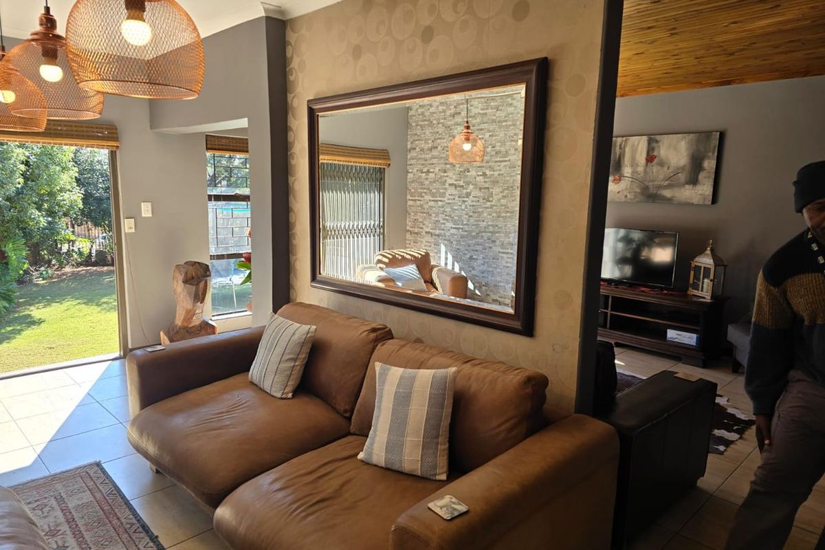A comfortable living area featuring tiled floors, a timber ceiling, and a stone feature wall, with direct access to the garden through a sliding door.