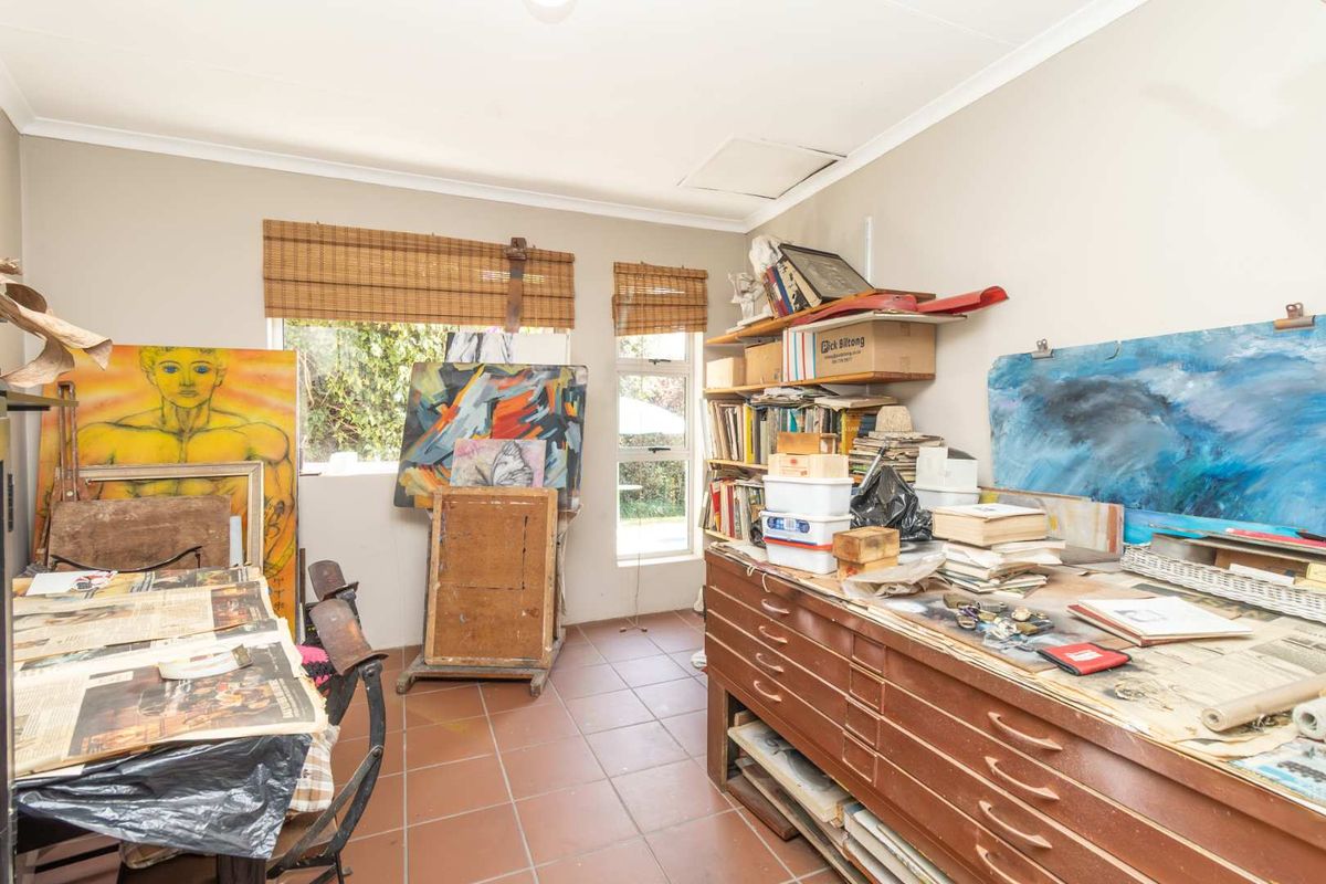 A functional room featuring tiled flooring and built-in shelving, currently utilized as an art studio space.