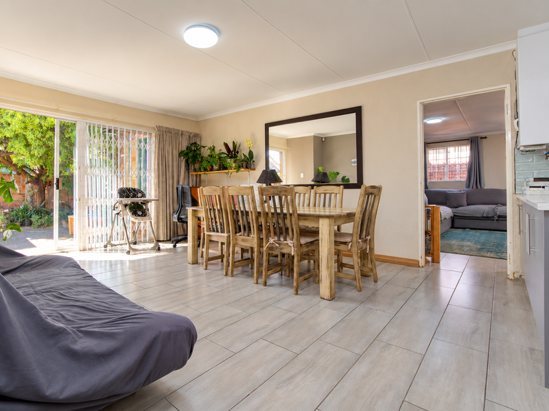 Spacious open-plan living and dining area featuring modern tiled floors, a sleek kitchen with quartz countertops, and direct access to a private outdoor patio.