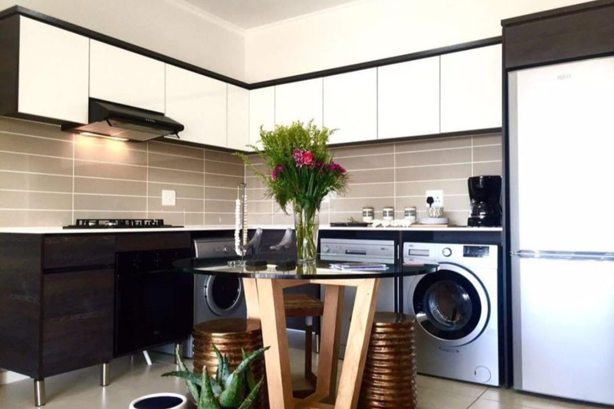 Modern kitchen featuring sleek two-tone cabinetry, tiled backsplash, built-in oven and hob, and integrated laundry appliances, offering a functional and contemporary cooking space.