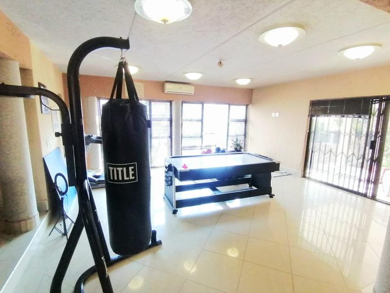 Spacious room currently utilized as a home gym, featuring tiled flooring, split-system air conditioning, and large windows providing ample natural light.
