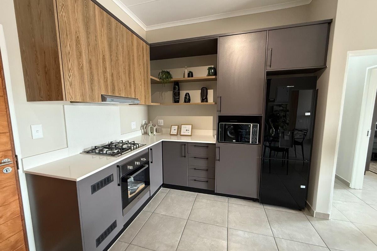Modern kitchen featuring two-tone cabinetry, stone countertops, built-in gas hob, oven, and integrated microwave space with tiled flooring.