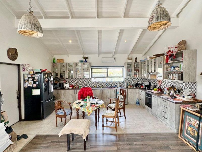 Spacious open-plan kitchen and living area featuring high exposed beam ceilings, extensive built-in cabinetry, and modern tiled flooring.
