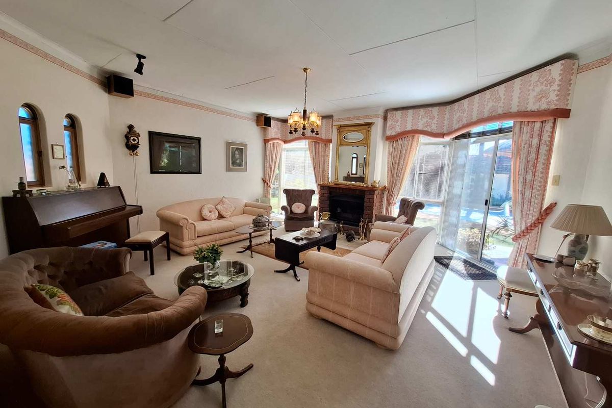 Spacious living room featuring a brick fireplace, arched windows, and sliding glass doors providing natural light and access to the outdoor area.
