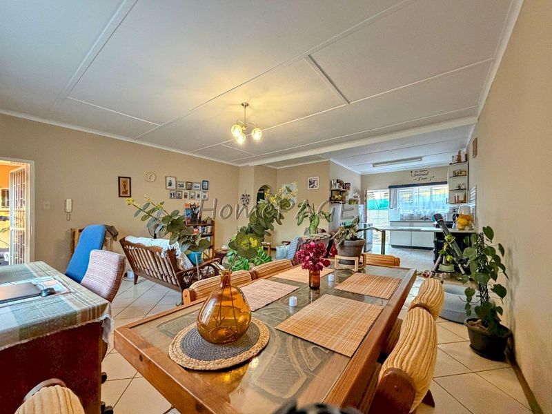 Spacious open-plan living and dining area flowing into a functional kitchen with tiled flooring and neutral wall finishes.