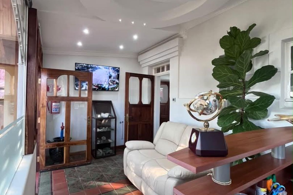 A well-lit office space featuring decorative ceiling details, terracotta tile flooring, and classic wooden door frames, creating a professional and inviting atmosphere.