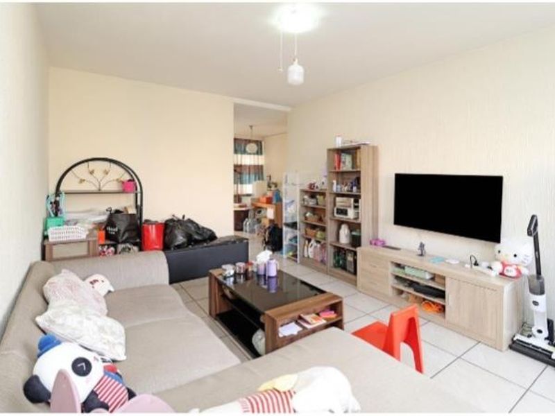 A functional living room featuring tiled flooring and neutral wall finishes, providing a comfortable space for relaxation and entertainment.