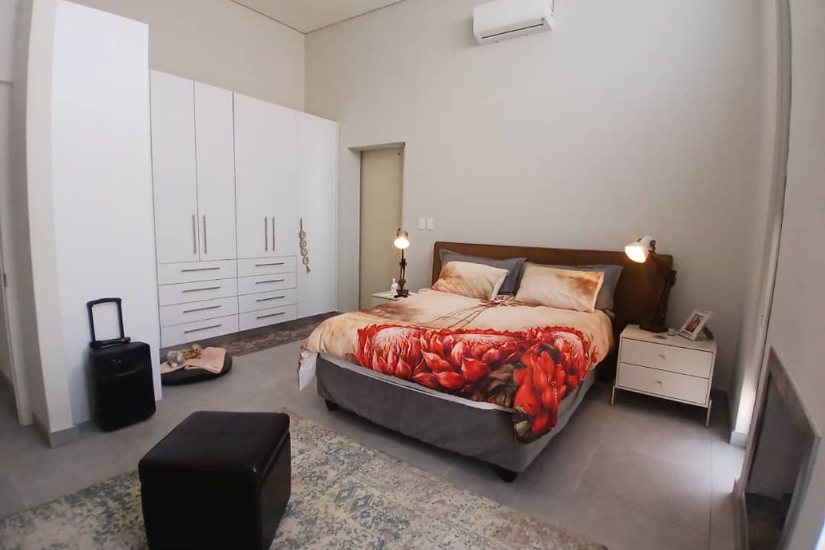 Spacious bedroom featuring modern built-in cupboards, tiled flooring, and a wall-mounted air conditioning unit.