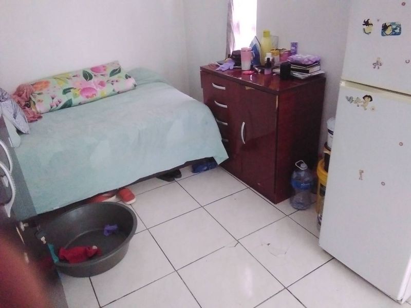 A small bedroom featuring tiled flooring with visible cracks, providing a basic living space.