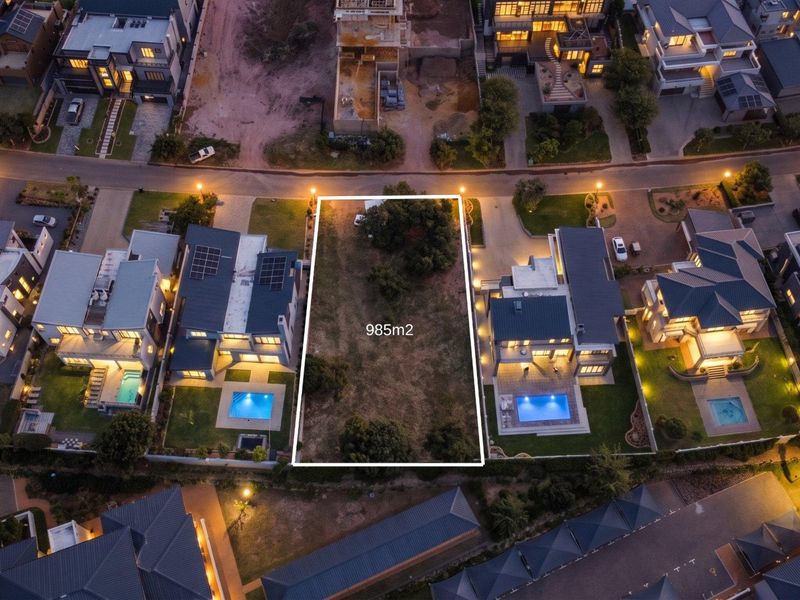 Aerial view of a 985m2 vacant residential plot situated within an established estate, surrounded by modern homes.