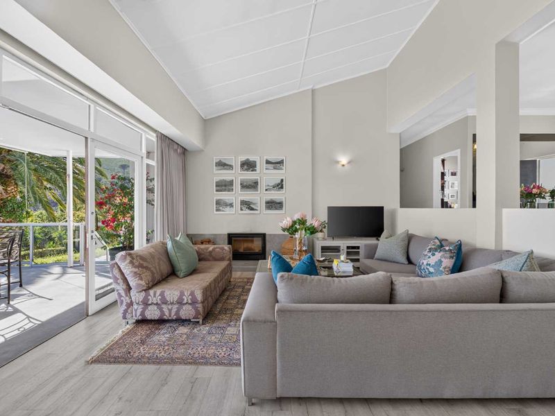 Spacious living room featuring a vaulted ceiling, built-in fireplace, and large sliding glass doors that open onto a covered patio area.