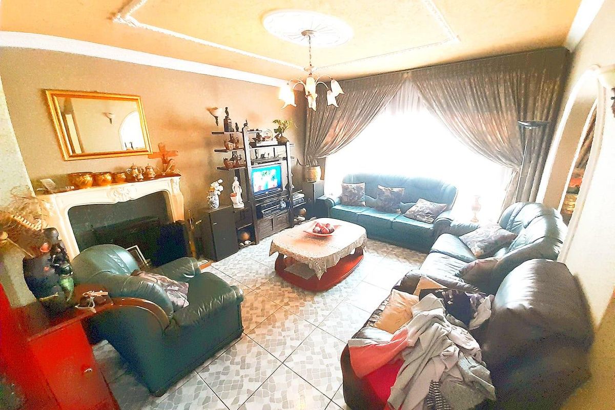 A living room featuring a fireplace, tiled flooring, and decorative ceiling molding, offering a traditional layout with natural light.