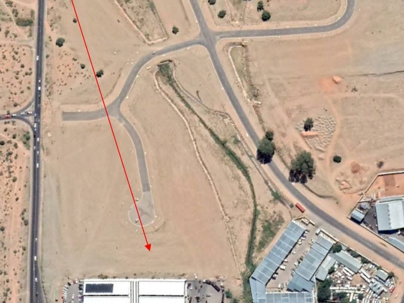 Aerial view of an industrial property site featuring a warehouse building with surrounding access roads and undeveloped land.