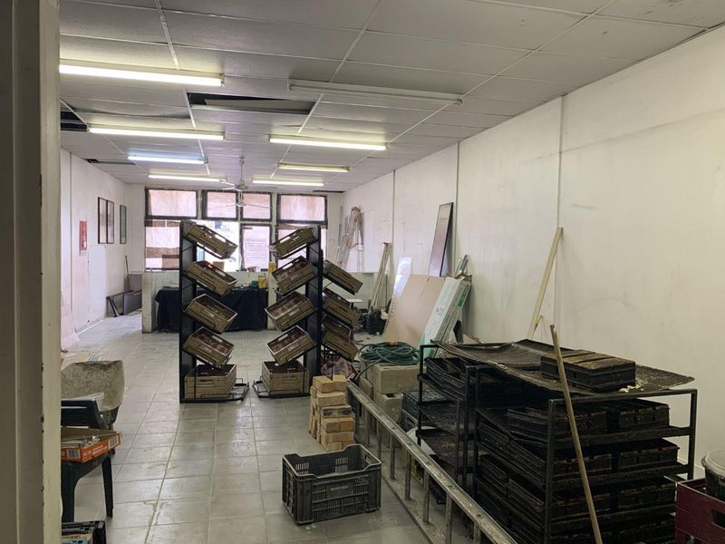 Open plan retail space featuring tiled flooring and suspended ceiling with fluorescent lighting, currently vacant and requiring cosmetic refurbishment.