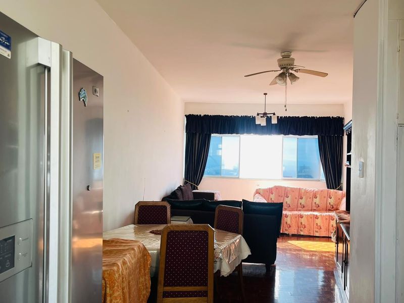 Open plan living and dining area featuring parquet flooring, a ceiling fan, and large windows providing natural light.