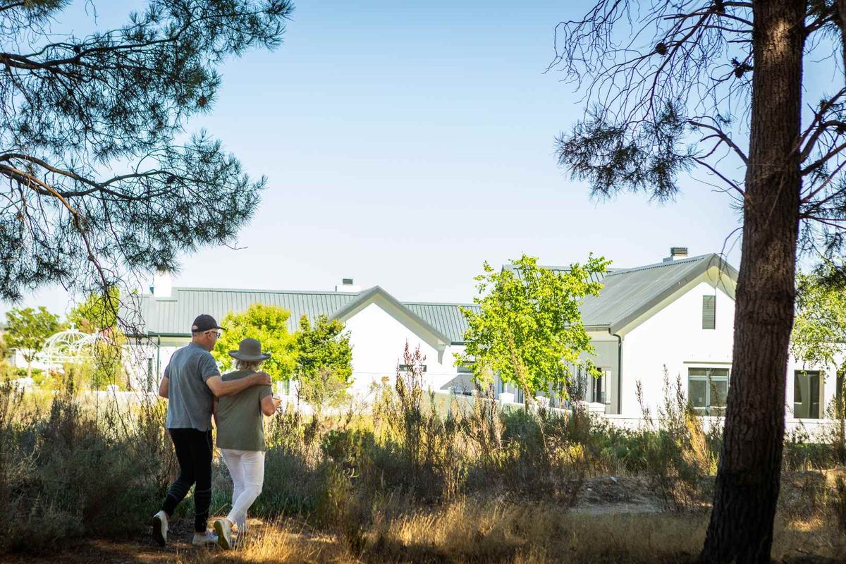 A view of the rear exterior of the property featuring a modern white facade and metal roofing, surrounded by natural landscaping.