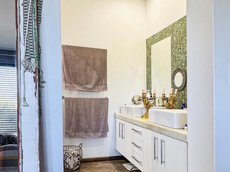 Modern bathroom featuring a double vanity with vessel sinks, mosaic tile backsplash, and polished concrete flooring.