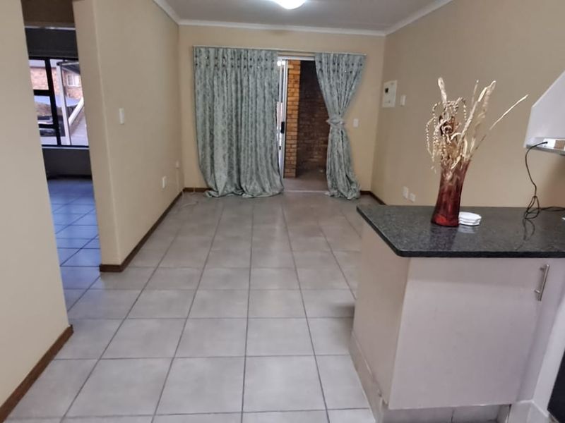 Open-plan living area featuring tiled floors, a functional kitchen with granite countertops, built-in oven and hob, and direct access to an outdoor patio area.