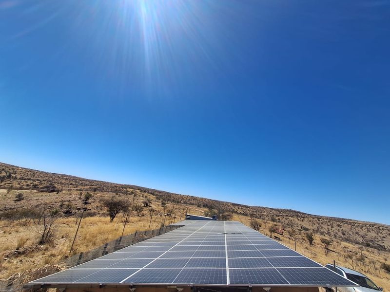 A large ground-mounted solar panel array situated in an open landscape, providing sustainable energy infrastructure for the small holding.