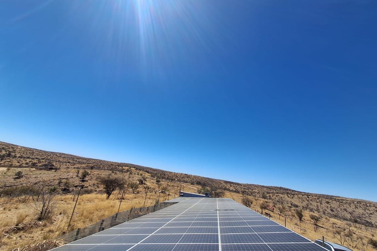 A large ground-mounted solar panel array situated in an open landscape, providing sustainable energy infrastructure for the small holding.