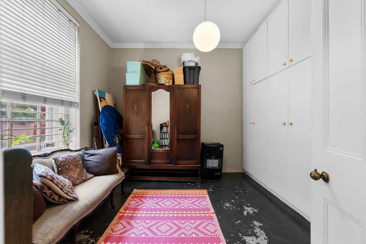 A bedroom featuring built-in floor-to-ceiling cupboards, venetian blinds, and decorative cornice detailing.