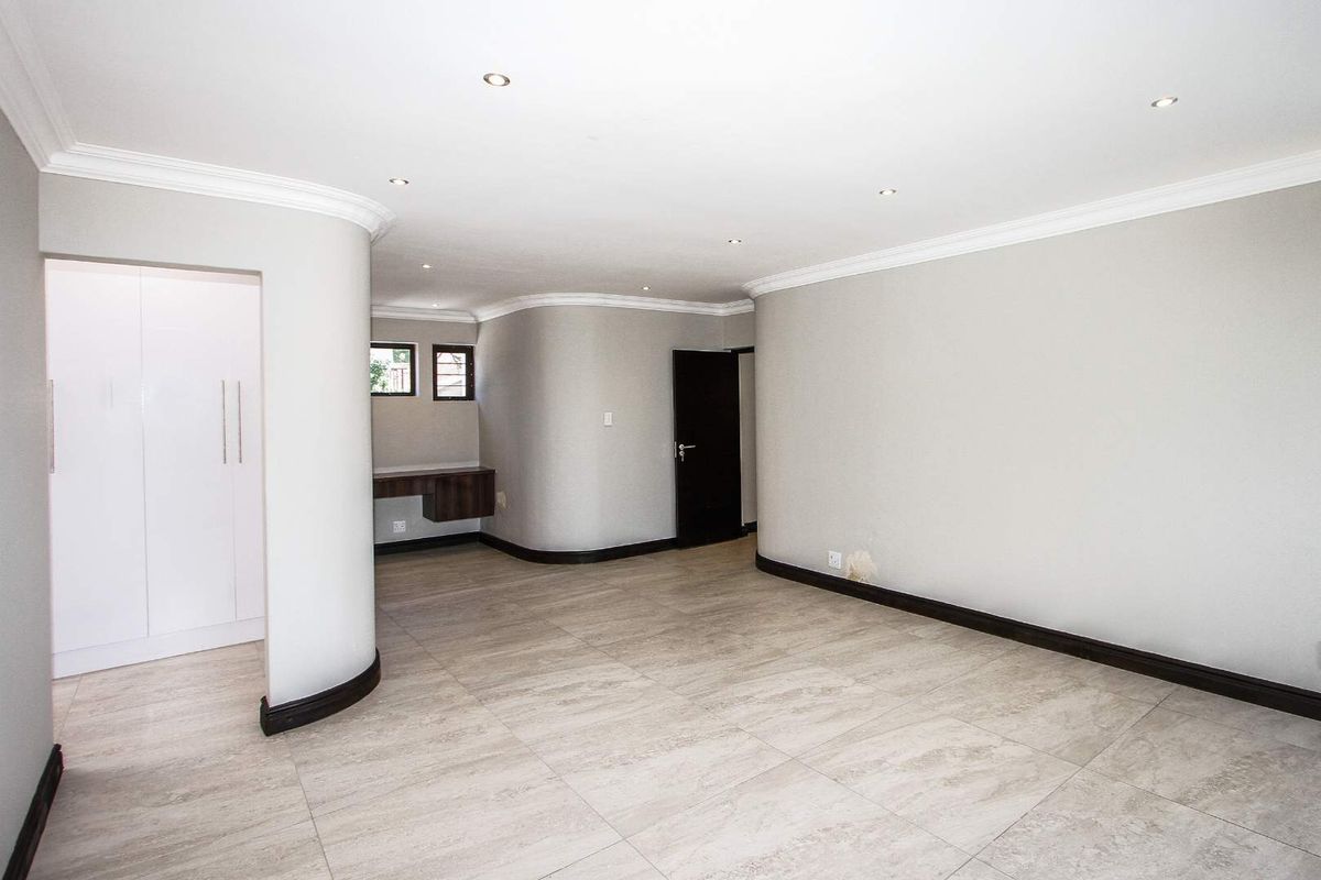 Spacious interior living area featuring neutral tiled flooring, recessed downlighting, curved wall architecture, and a built-in desk nook.
