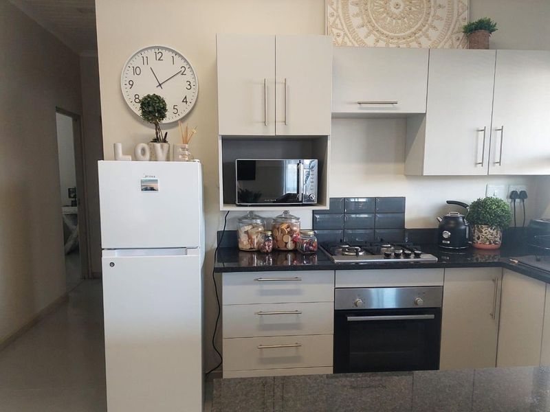 A functional kitchen featuring modern white cabinetry, dark granite countertops, a gas hob, and a built-in oven with a tiled backsplash.