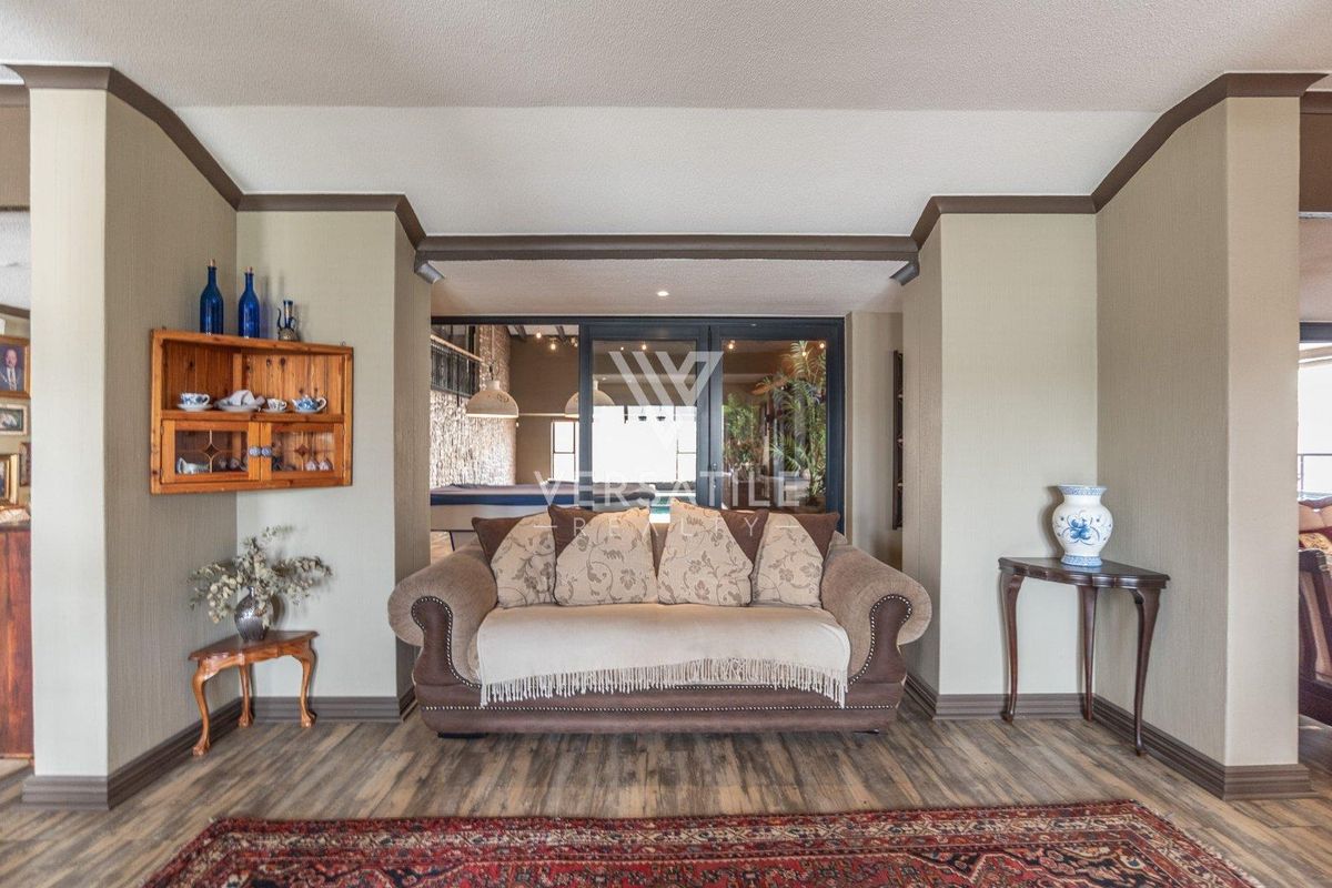 A well-maintained living room featuring laminate flooring, neutral wall tones, and large sliding glass doors that provide a view into the adjacent entertainment area.