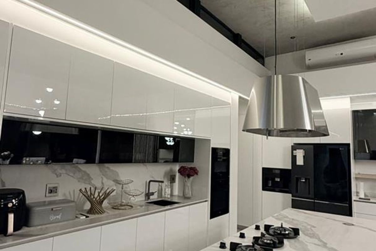 Modern kitchen featuring a large marble-topped island with integrated gas hob, sleek high-gloss cabinetry, and sophisticated recessed ceiling lighting.