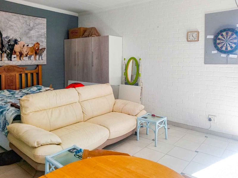 A living area featuring tiled flooring and a painted brick feature wall, providing a functional space with neutral finishes.