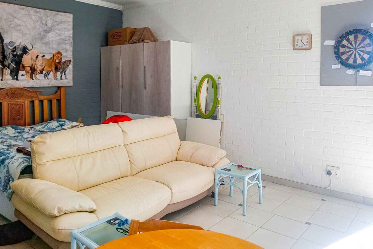A living area featuring tiled flooring and a painted brick feature wall, providing a functional space with neutral finishes.