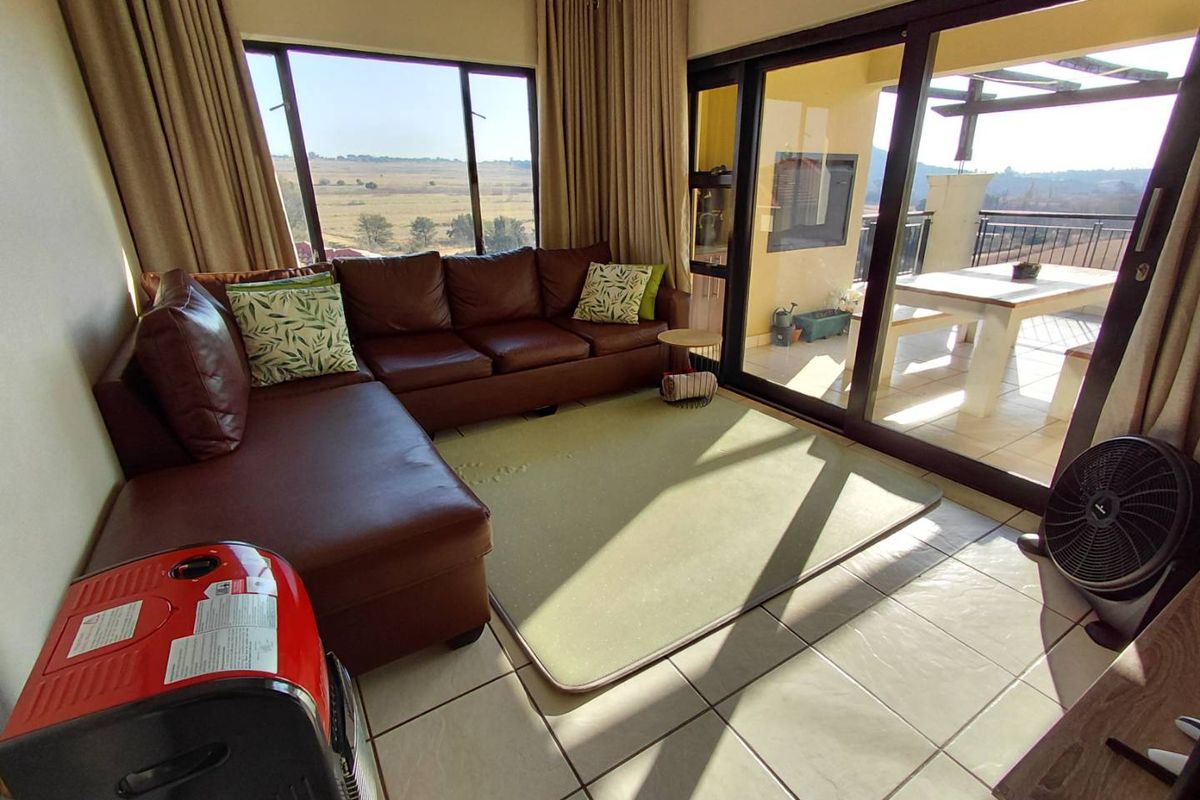 A bright living room featuring large windows and sliding glass doors that open onto a spacious balcony with scenic views.