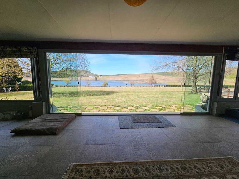 Spacious living area featuring expansive floor-to-ceiling sliding glass doors that provide panoramic views of the surrounding farm landscape and lake.
