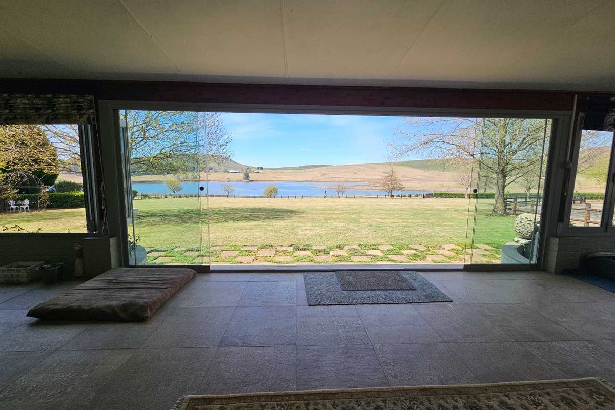 Spacious living area featuring expansive floor-to-ceiling sliding glass doors that provide panoramic views of the surrounding farm landscape and lake.