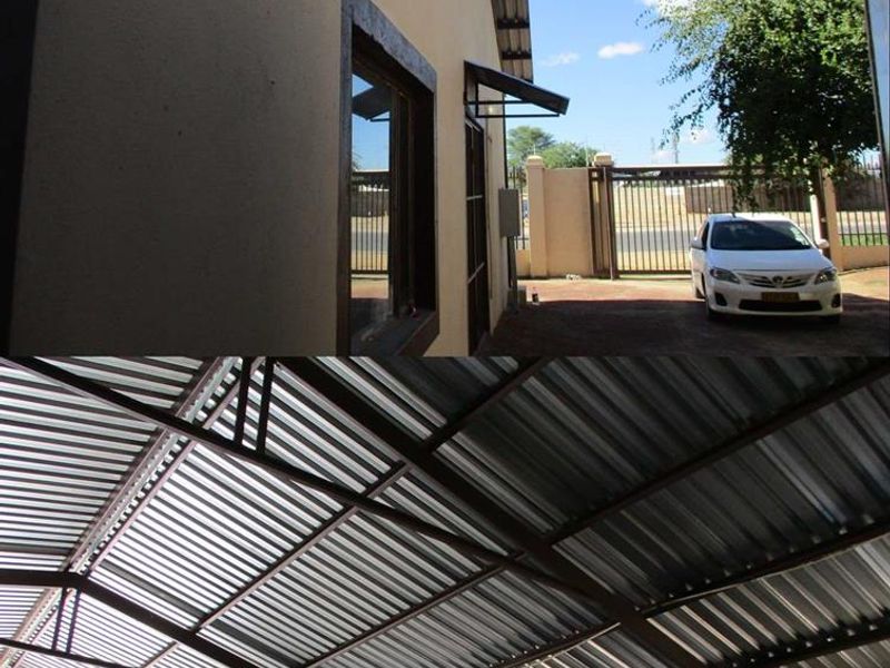 Industrial property exterior featuring a corrugated metal roof structure, secure perimeter fencing, and paved driveway access.