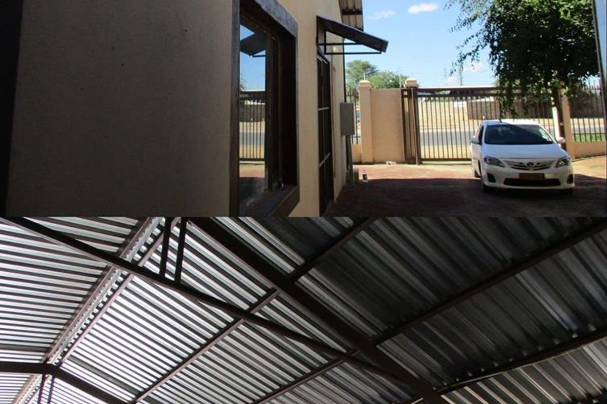 Industrial property exterior featuring a corrugated metal roof structure, secure perimeter fencing, and paved driveway access.