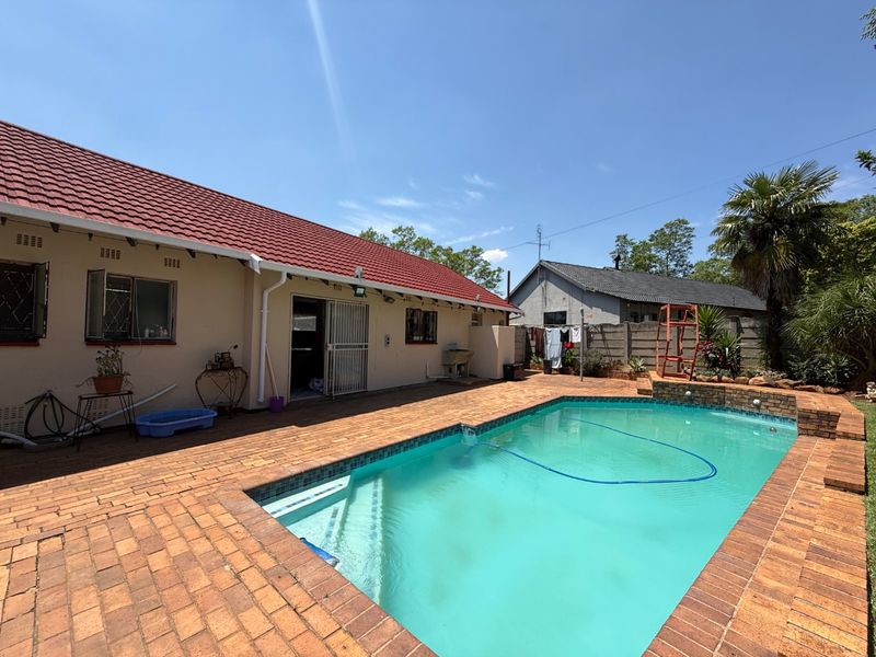 Rear garden area featuring a swimming pool with brick paved surround and direct access to the main dwelling.