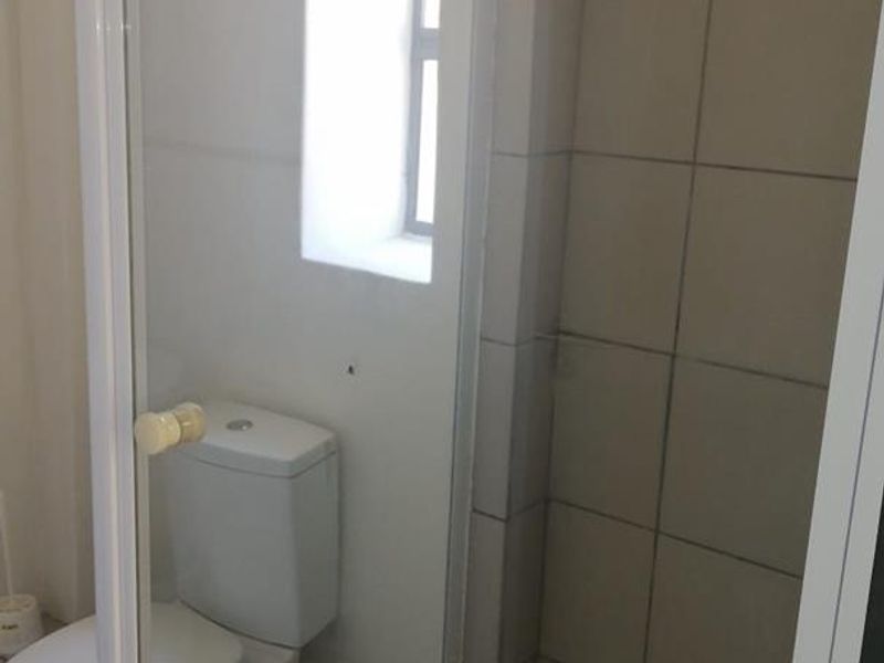 A functional bathroom featuring a tiled shower enclosure and a standard toilet, providing essential sanitary facilities.