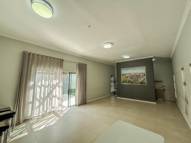 Spacious open-plan living area featuring tiled flooring, recessed ceiling lighting, and large sliding glass doors providing access to the outdoor patio area.