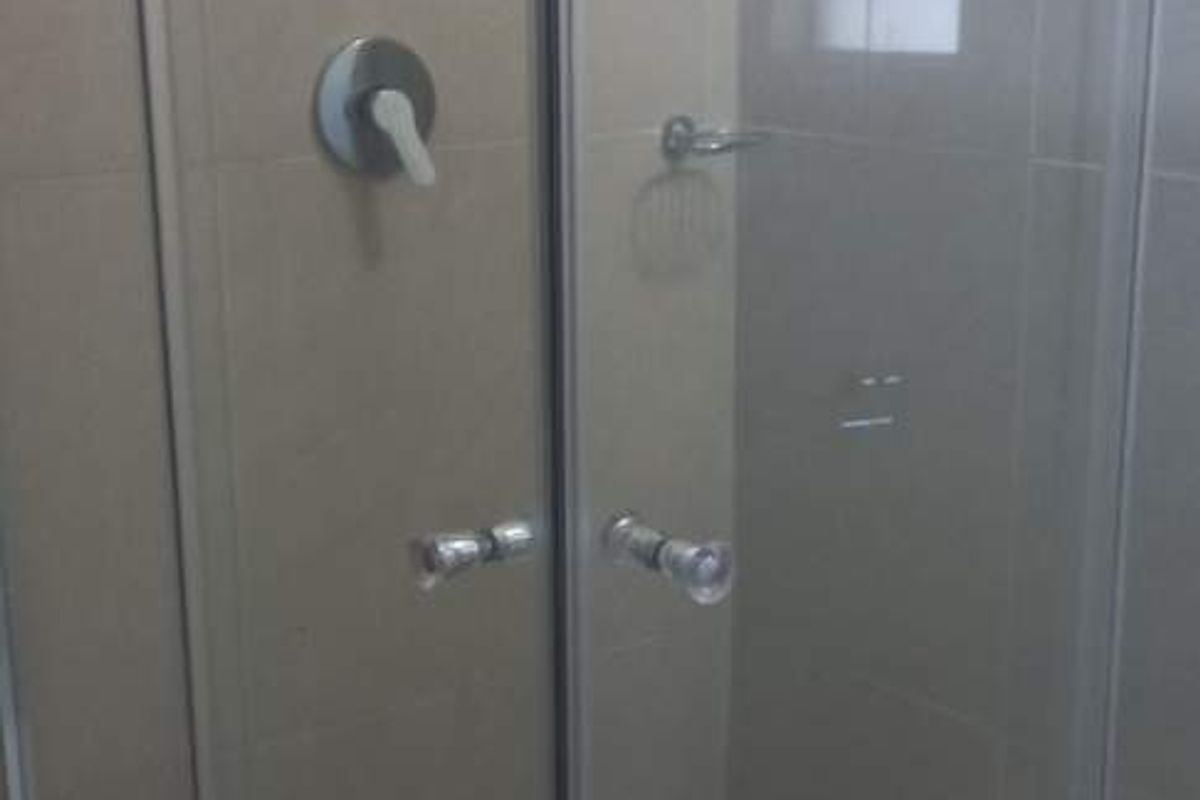 A functional shower enclosure featuring a glass door, tiled walls, and a built-in shower mixer.