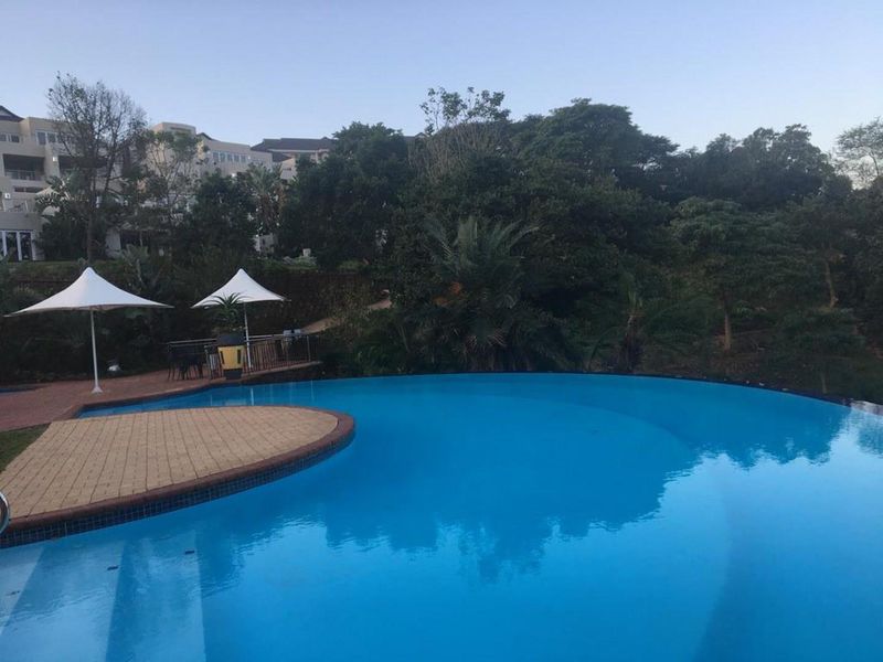 A well-maintained outdoor swimming pool area featuring a paved deck and landscaped surroundings, offering a tranquil communal space.