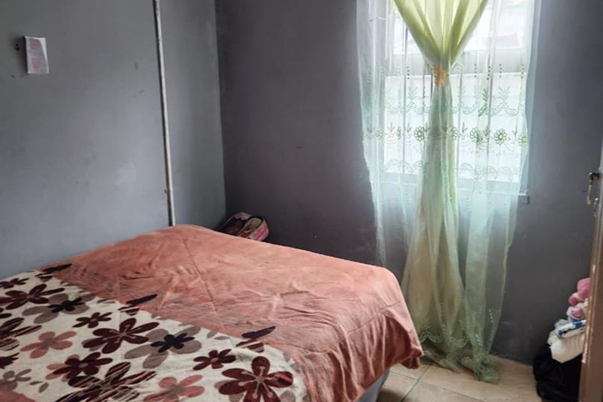 A compact bedroom featuring tiled flooring and a window, currently requiring cosmetic updates to the wall finishes.